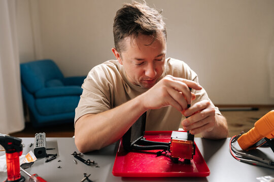 Portrait of skilled young man repairing and inspecting all-in-one pc liquid cooler at home, servicing radiator, pump and tubing to maintain performance and upgrade desktop cooling system.