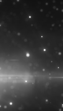Monochrome floating particles and soft bokeh lights forming an atmospheric abstract background.