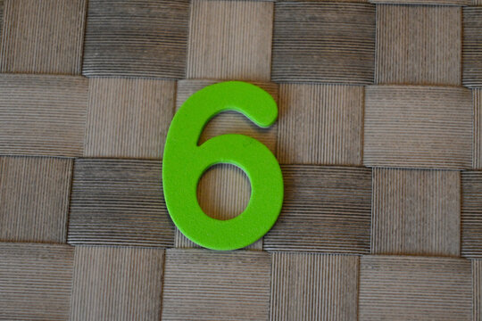 Green number six sign on woven mat