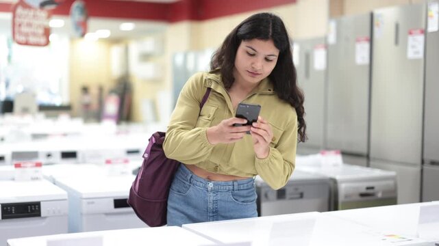Woman choosing washing machine scans QR code on the price tag to check the technical specifications . High quality 4k footage