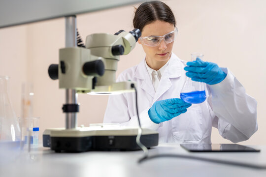 Female scientist using a microscope while conducting scientific research and analyzing samples
