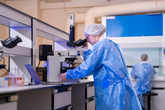 Young female researcher working in the lab, she is examining the samples under a microscope