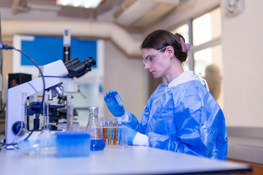 Female scientist using a microscope while conducting scientific research and analyzing samples