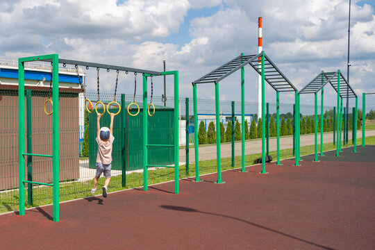 child playing on monkey bars in a colorful outdoor playground setting with metal and plastic structures, active and playful mood, side view, green and yellow tones.