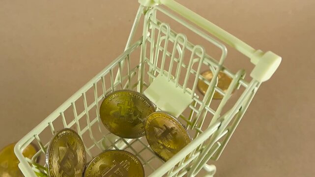 Miniature shopping cart filling up with golden bitcoin coins representing the concept of cryptocurrency purchase, digital currency investment, and modern electronic finance trading