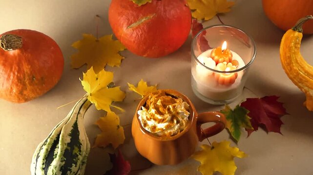Aromatic pumpkin spice latte with whipped cream and cinnamon surrounded by autumn leaves, seasonal gourds, and a burning candle, creating a warm and inviting fall atmosphere