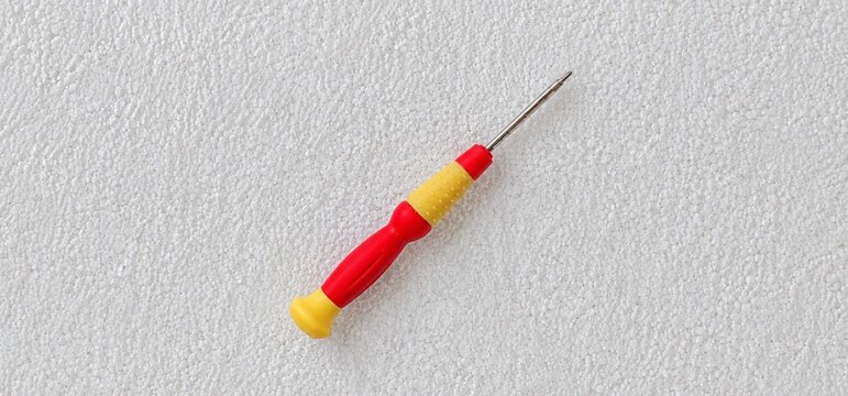 Small Precision Screwdriver on White Textured Surface