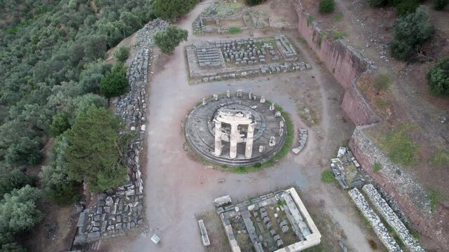 Aerial view of the Tholos of Delphi ancient temple surrounded by historic ruins and olive trees in Delphi, Greece.