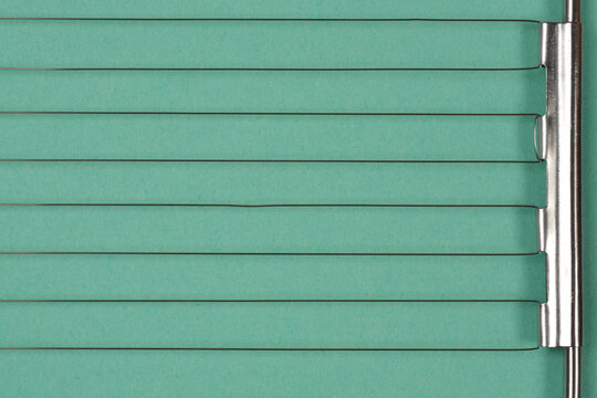A horizontal macro close up shot showing the parallel stainless steel cutting wires of an egg slicer on a green background.