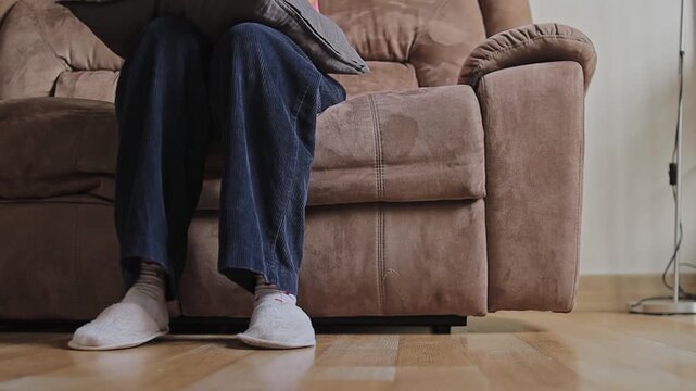 Low-angle view of women leg with slippers fidgeting resting on couch
