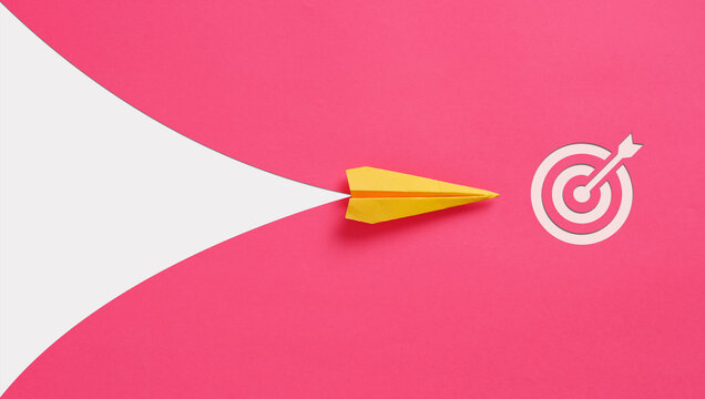 Yellow paper airplane flying towards target on pink background