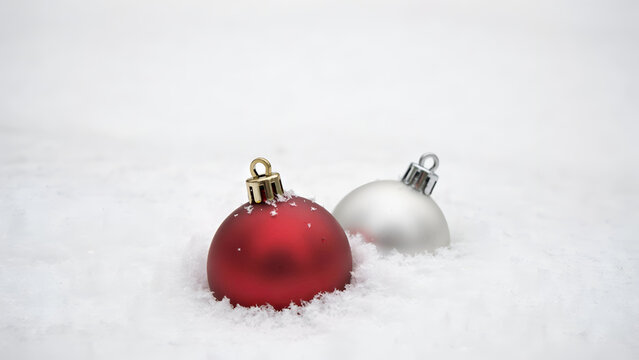 Red and silver christmas ornaments resting in fresh white snow