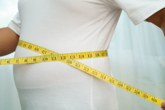 Asian woman with fat belly big size overweight and obesity with measure tape.