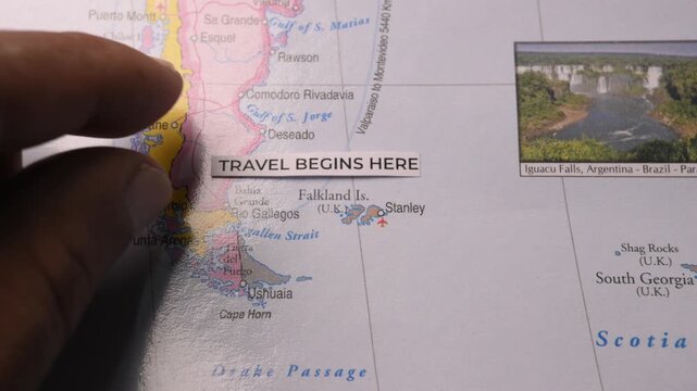 Hand Placing Travel Begins Here Label on South America Map