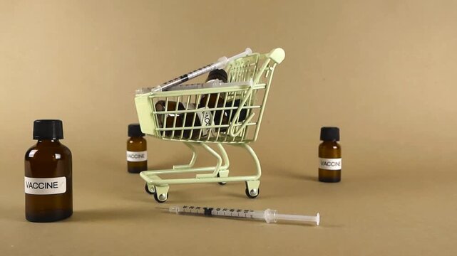 Miniature shopping cart full of vaccine vials and syringes, conceptualizing the commercialization, cost, and distribution of immunization treatments against diseases like coronavirus