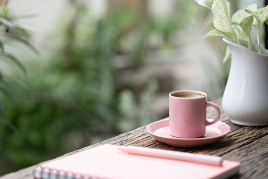 Pink coffee cup and pink pen pen and book on old wooden table