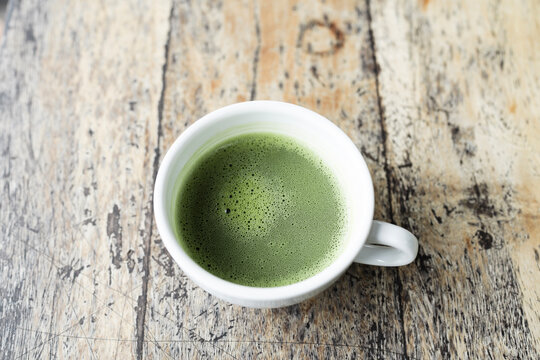 Matcha in a white cup top view on grunge wooden table
