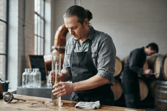 Distiller taking a hydrometer reading from the still
