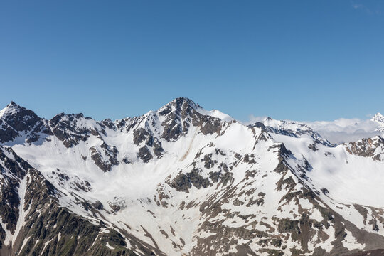Wide panoramic mountain landscape seen from cable car lifts on Mount Elbrus, Kabardino-Balkaria, Russia, with rugged snowy peaks, glaciers, and clear blue sky