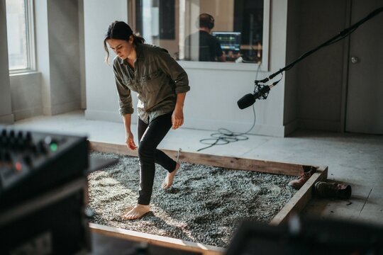 Foley artist recording footsteps on a tray of gravel