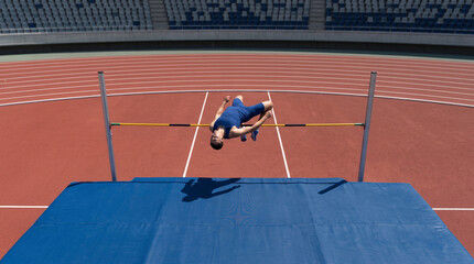 Obraz premium Top view of athlete in solid clothing clearing the bar in high jump, close-up concept of flight technique, agility, and sports achievement