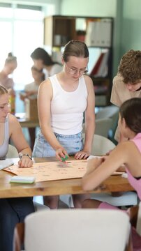 Group of teens playing board game. Teenagers have fun during meetings and gatherings, enthusiastically and excitedly fulfill conditions of game 