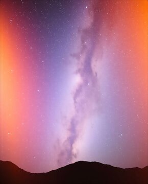 Vibrant Milky Way galaxy arching over dark mountain silhouettes.