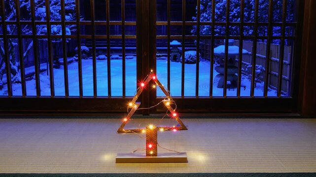 雪降る中庭を望む和室の格子窓と畳の上に置かれた組子細工クリスマスツリーの温かいイルミネーション