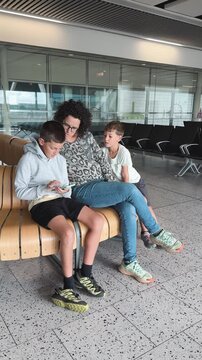 Mother and sons waiting together at airport terminal