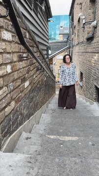 Woman walking up narrow brick alley stairs
