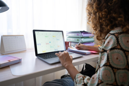 White woman working in home office at desk with laptop and calendar