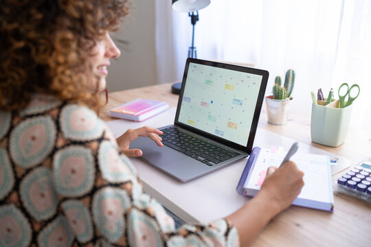 White woman planning schedule on laptop and notebook