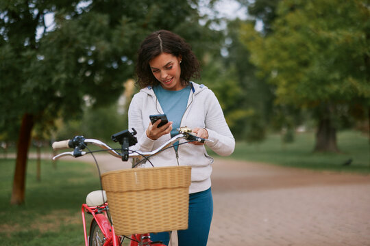 Woman talking on smartphone beside bicycle in autumn park