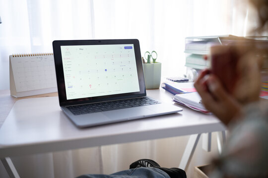 Laptop showing calendar on desk in home office setting