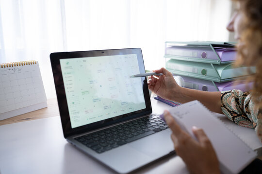 White person using laptop and notebook for schedule planning