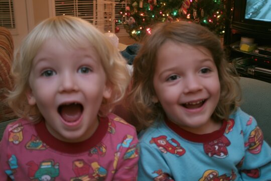 Excited children celebrating Christmas in pajamas by tree