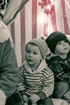 Two Young Boys Sitting Near Santa Claus in Holiday Setting