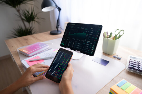 White person analyzing stock market data on smartphone and tablet