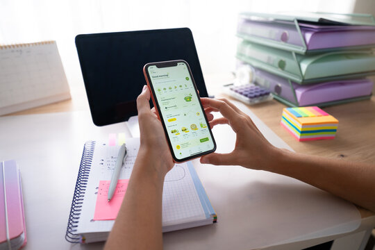 Hands holding smartphone with food delivery app over desk