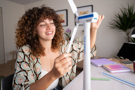 White woman assembling wind turbine model at home desk in Spain