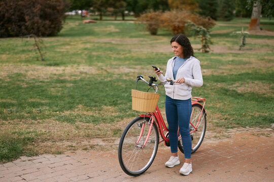 Woman with bicycle using smartphone in autumn park