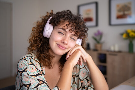 White woman with headphones smiling indoors in a home setting