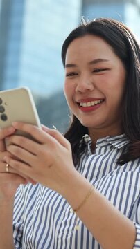 close up young asian businesswoman hold smartphone and looking outside during relax outside office for people lifestyle and technology concept