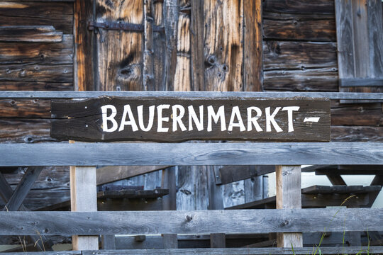 Schild Bauernmarkt aus Holz vor rustikalem Holzhintergrund