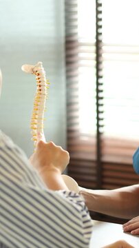 physical therapist hand pointing on human skeleton at middle back to advise and consult to patient to treatment at office for healthcare and telemedicine concept