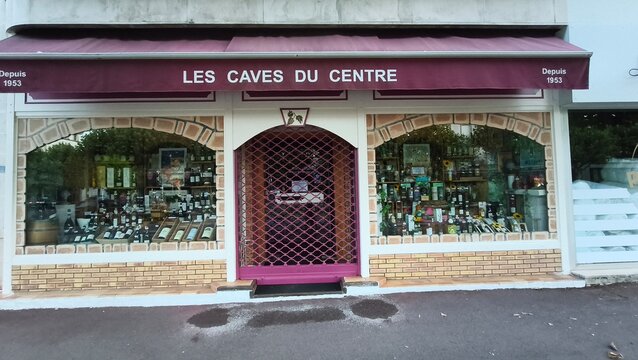 Royan, France - July 15, 2026: Charente-Maritime. Nouvelle-Aquitaine. Wine shop facade with large windows displaying various bottles and a decorative entrance, Les Caves du Centre, since 1953