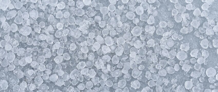 Close up texture of frozen sleet and ice pellets on ground. Winter weather graupel background