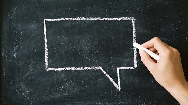 Hand drawing a white speech bubble on a black chalkboard with chalk for communication concepts