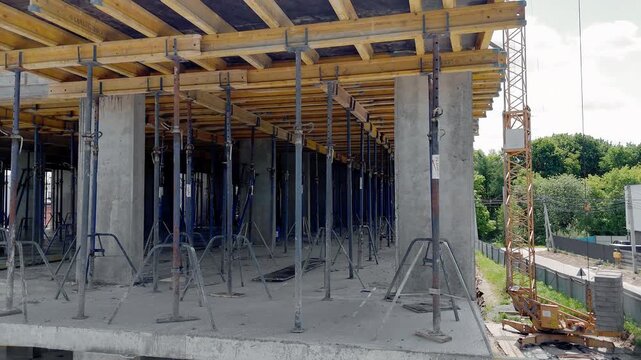 Dense temporary supports hold wooden formwork beneath a concrete floor, Construction progress highlights concrete structures labor and urban growth