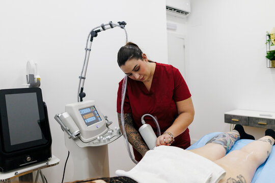 Specialist performing body contouring treatment on client leg
